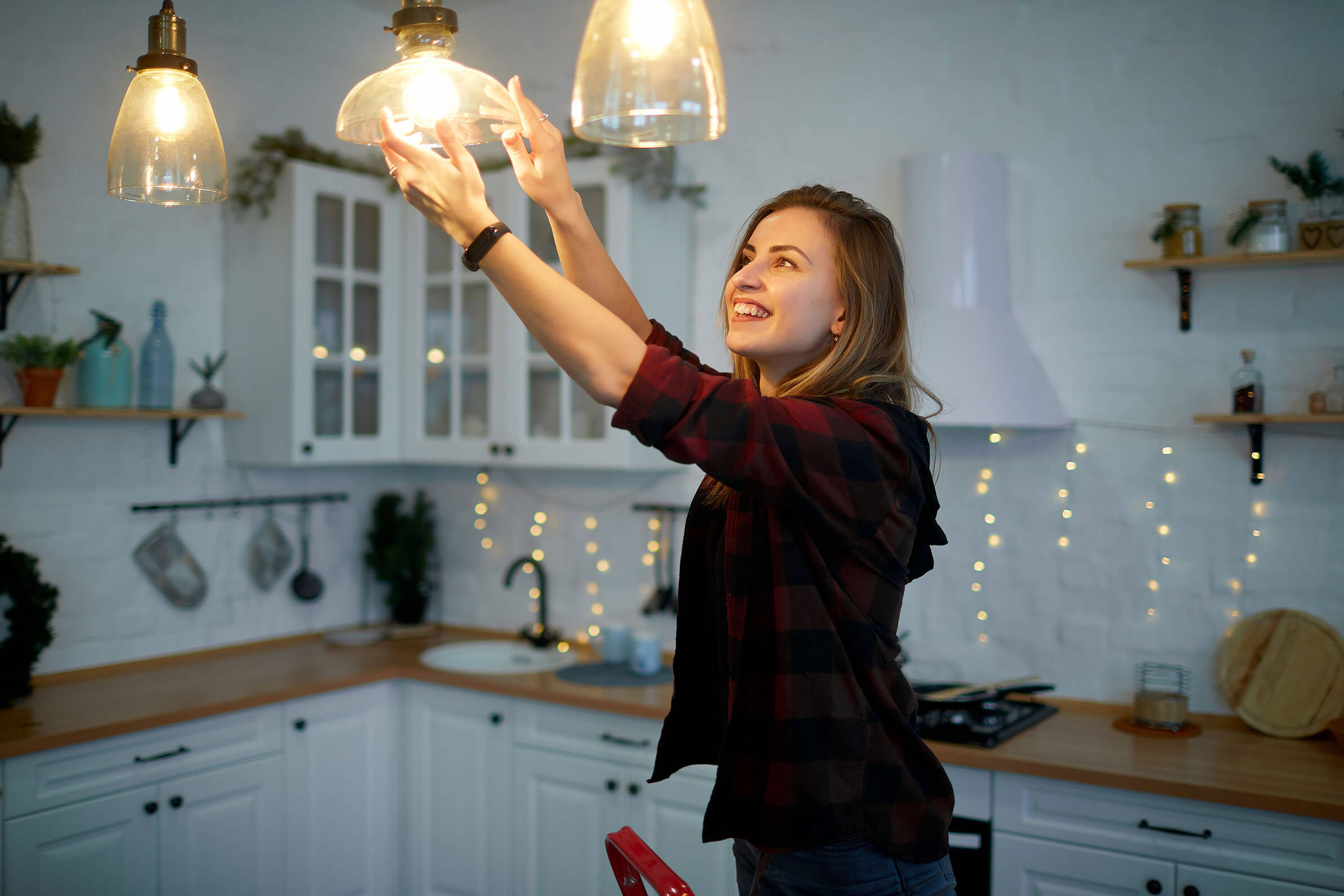 Woman changing a lightbulb in a kitchen