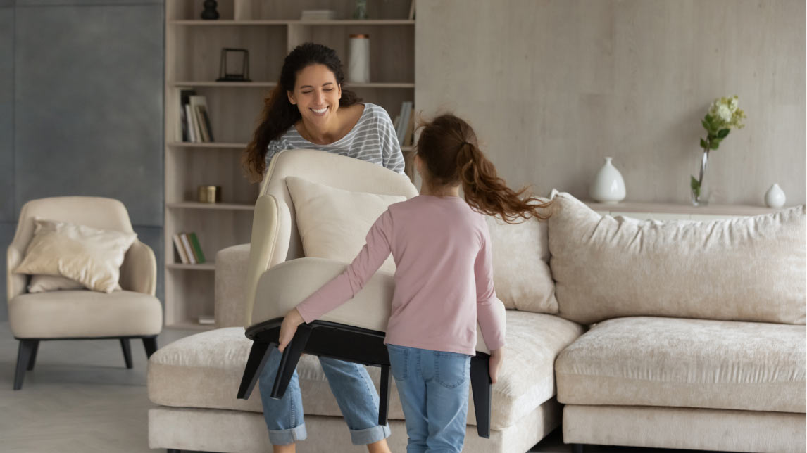 A mother an daughter rearranging furniture in a living room